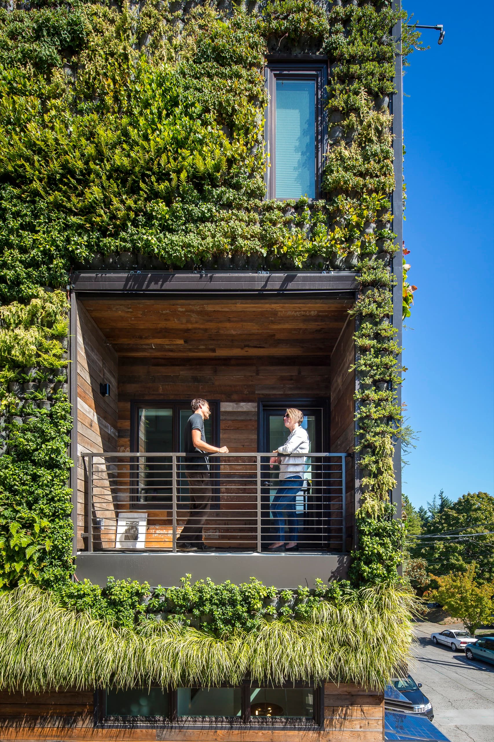 Woodlawn balcony framed by a lush living wall, with two residents standing at the railing, Woodlawn, Portland